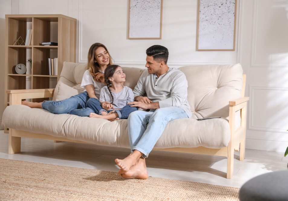 Happy,Family,With,Little,Daughter,Sitting,On,Sofa,In,Living